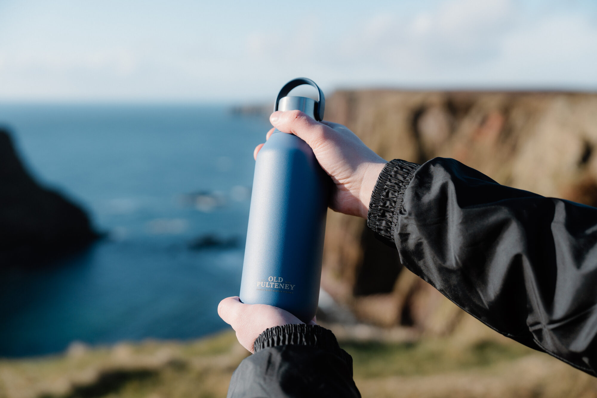 Holding a Old Pulteney Chillys bottle by the Duncansby Stacks in Wick